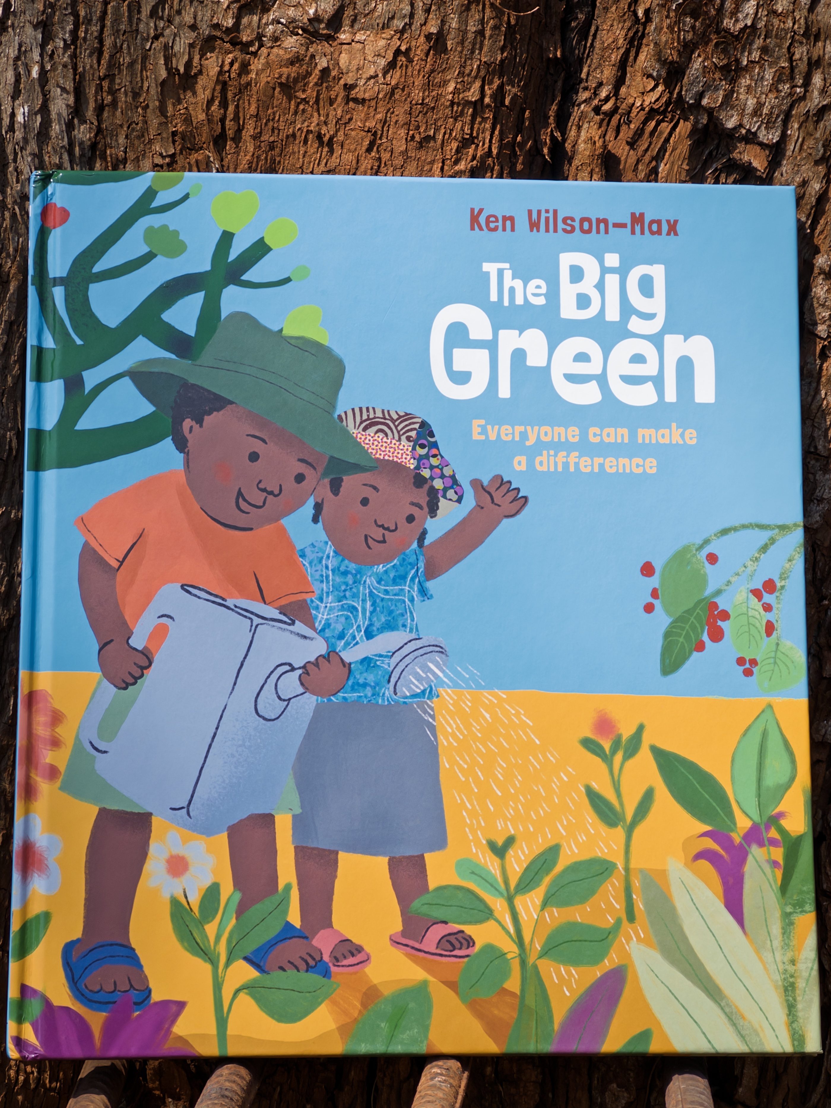 Photo of the cover of The Big Green against a jacaranda tree.